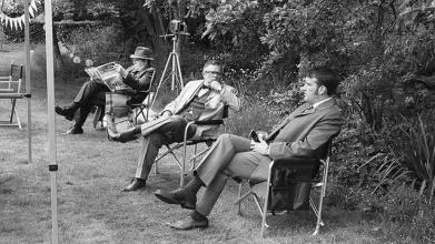 Men in deck chairs, reading, talking, grey 